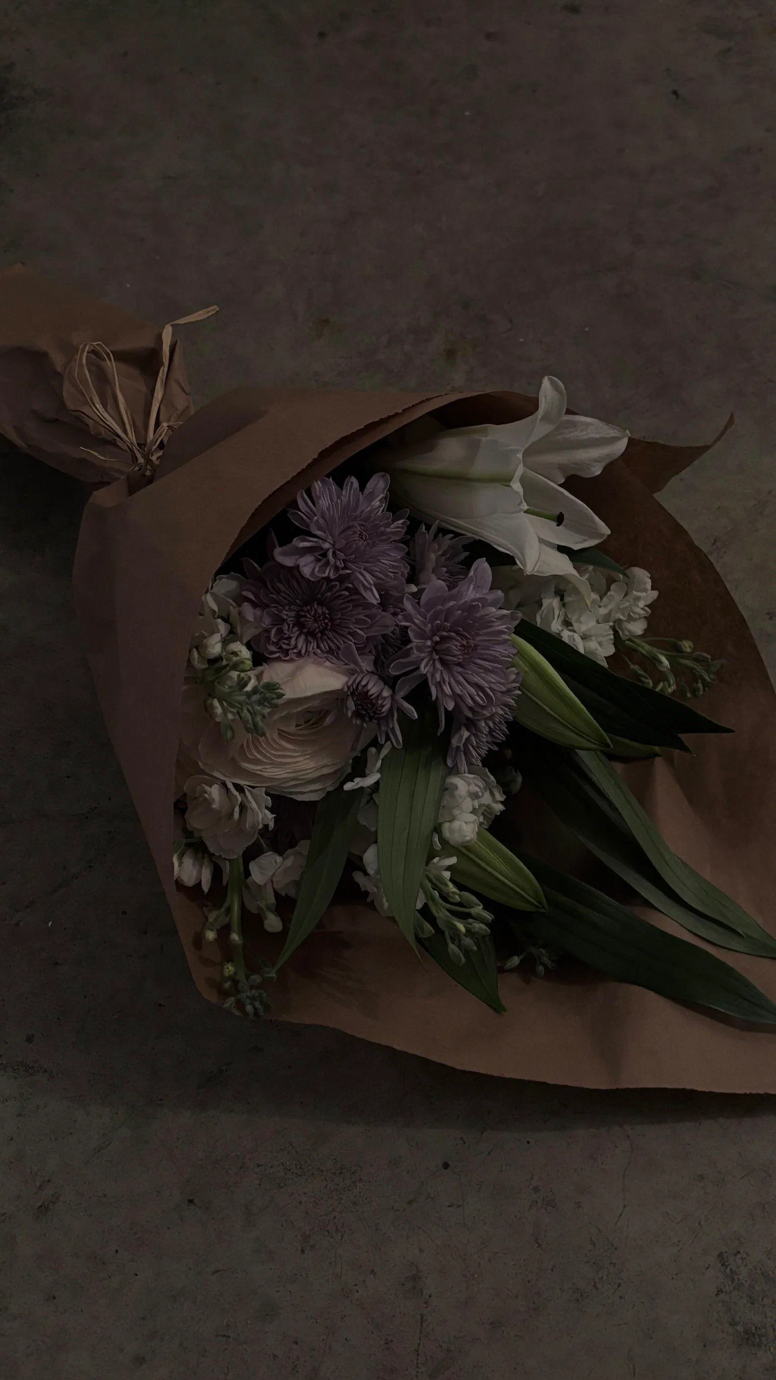 A bouquet in brown paper on a concrete floor, February 2026.