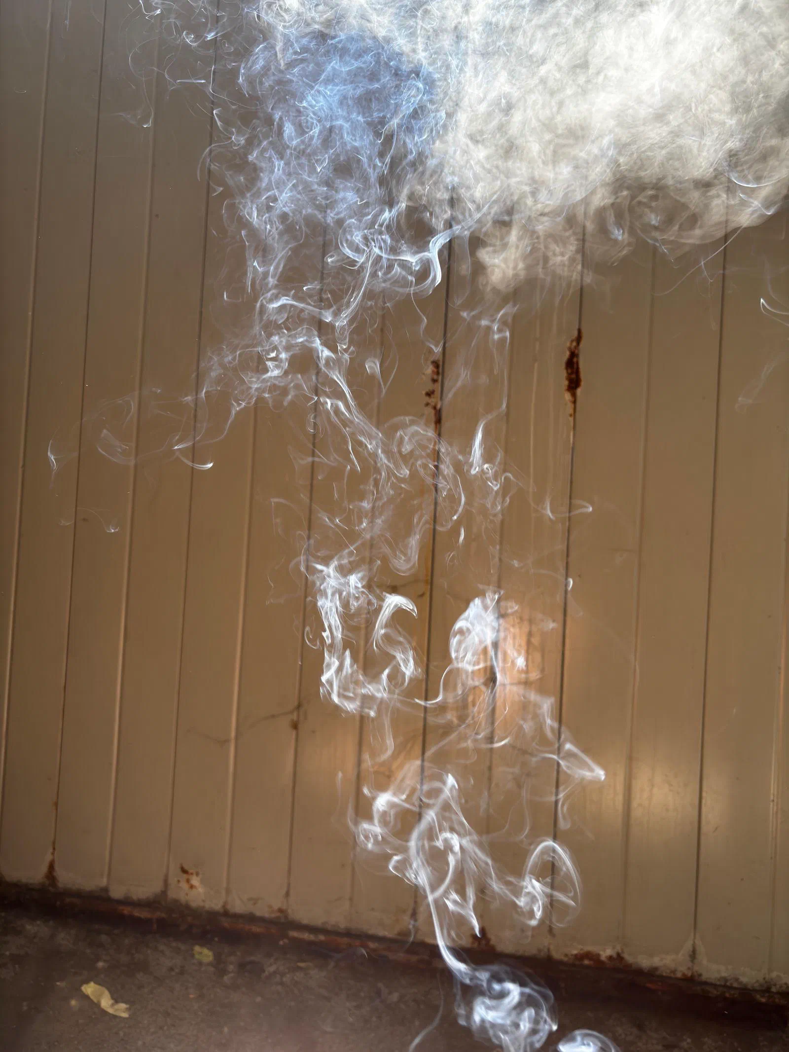 Smoke rising against a metal wall, July 2026.