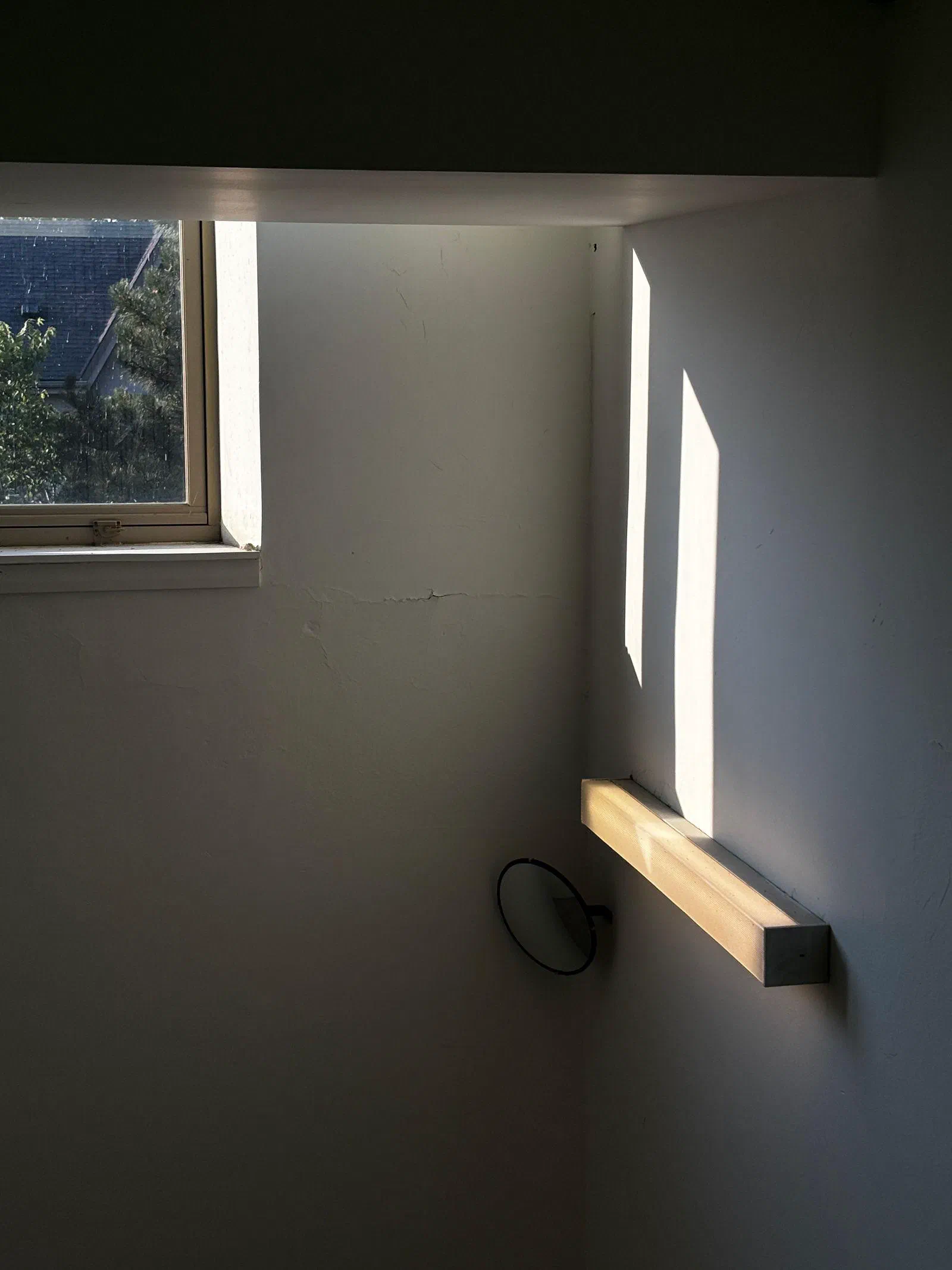 Sunlight from a small window falling on a white wall, August 2026.