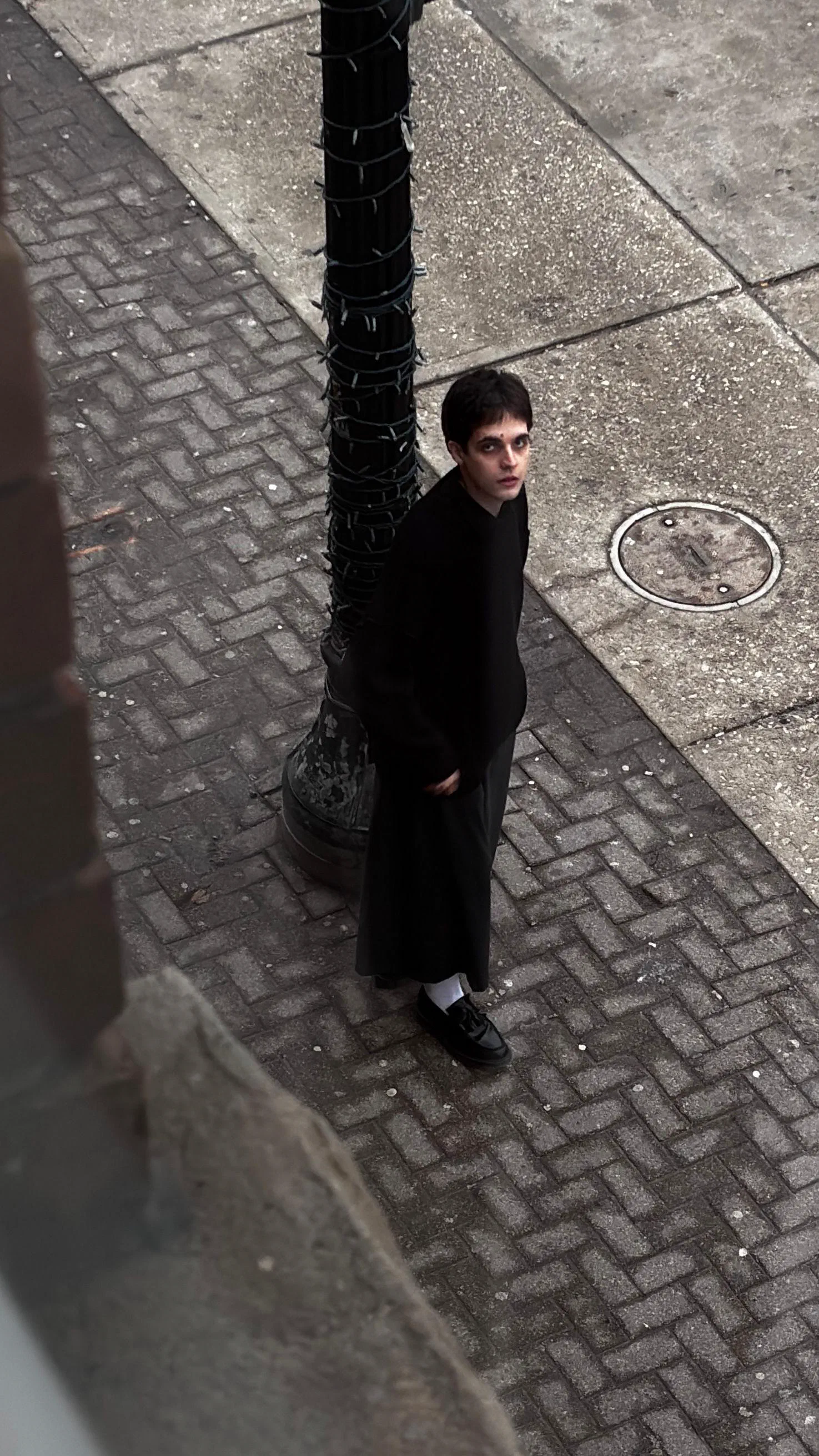 Andrada beside a lamppost wrapped in string lights, looking up at the camera, March 2026.