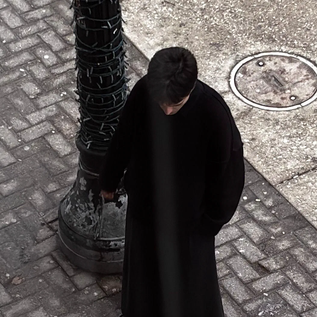 A closer view of the same moment: Andrada, head bowed, beside the lamppost.